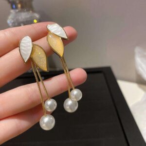 A pair of leaf-shaped dangle earrings with pearls. The leaves are white and shimmery gold